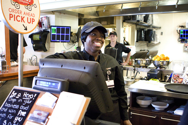 Decorative: an image of a fast food worker in uniform, at a cash register.